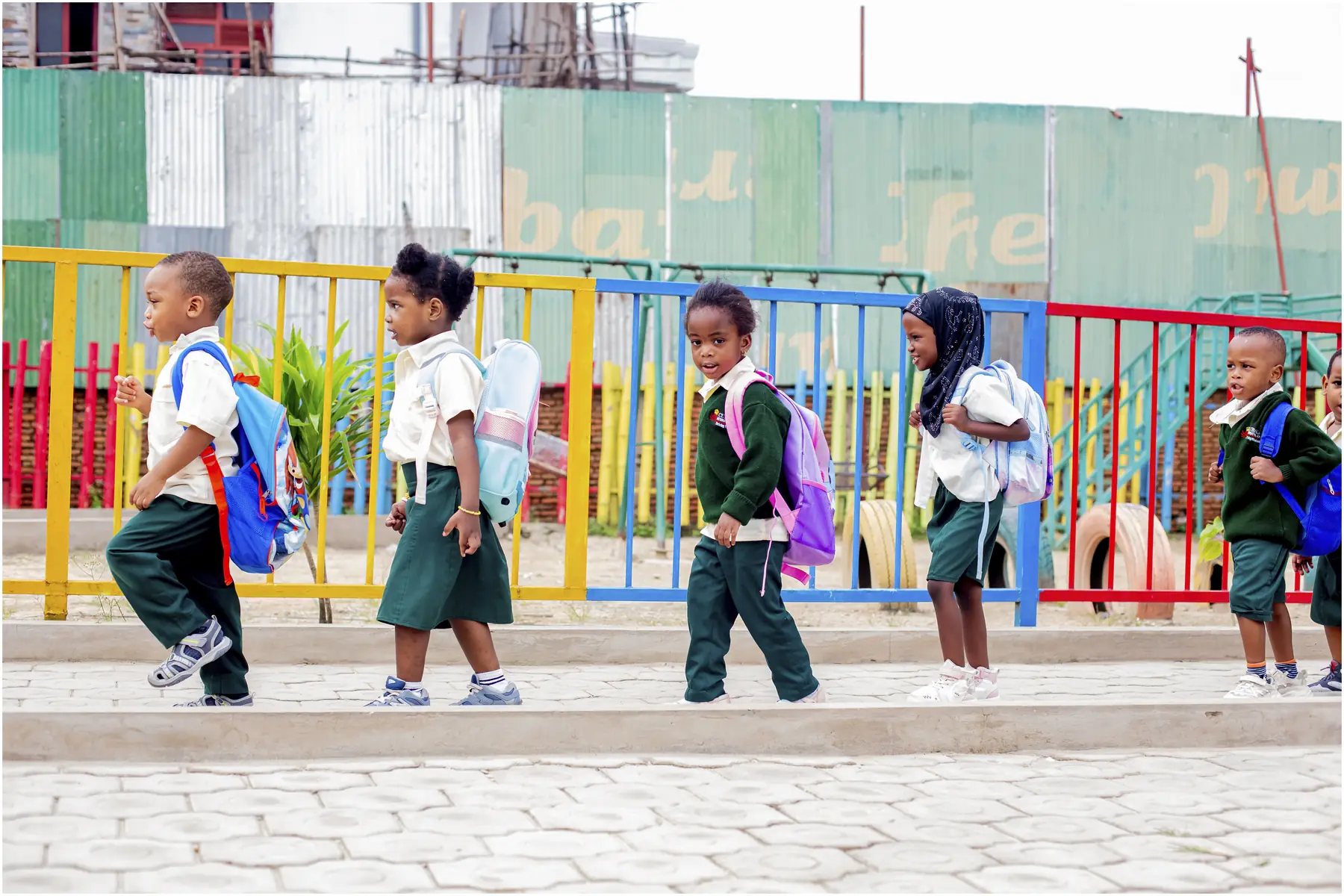 Kindergarten pupils walking with backpacks on campus